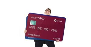 (man holding giant credit cards indicating he’s in a lot of debt)
