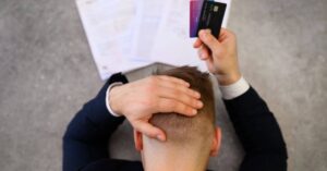 (stressed man holding credit cards)