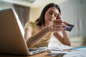 (woman stressed, staring at a credit card)