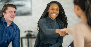 (Smiling woman shaking hands in a professional setting, symbolizing trust, agreement, and support during a financial or legal consultation.)