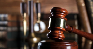 (Close-up of a judge’s gavel with law books and scales in the background, symbolizing legal action and courtroom consequences related to debt.)