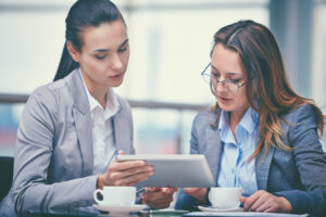 Businesswoman presenting project to investor. Serious female employee showing content on tablet to colleague, explaining details. Communication or teamwork concept